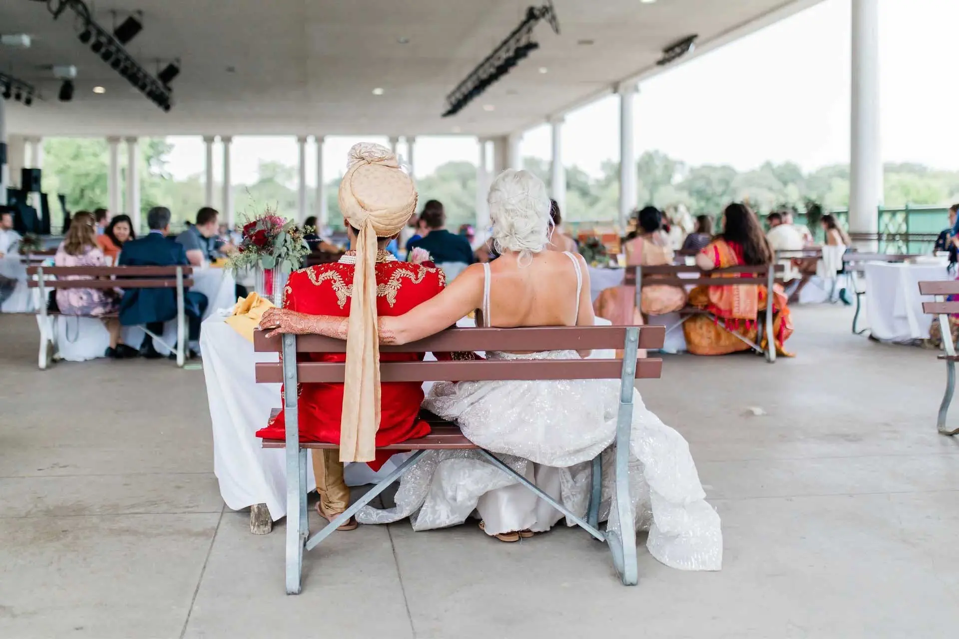 Bride and groom sitting on a bench overlooking their guest on the promenade of Como Lakeside Pavilion
